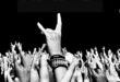 Pra Cego Ver: Foto de várias mãos erguidas fazendo gestos de rock and roll