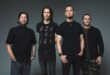 Pra Cego Ver: Foto colorida mostra os integrantes da banda Alter Bridge. Todos estão de camisetas pretas e em pé