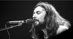 Pra Cego Ver: Foto em preto e branco mostra o músico Rick Davies tocando piano e cantando. Ele está de barba e cabelo comprido