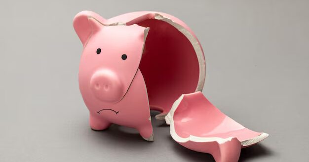 Pra Cego Ver: A imagem é um cofinho de porco rosa quebrado e vazio